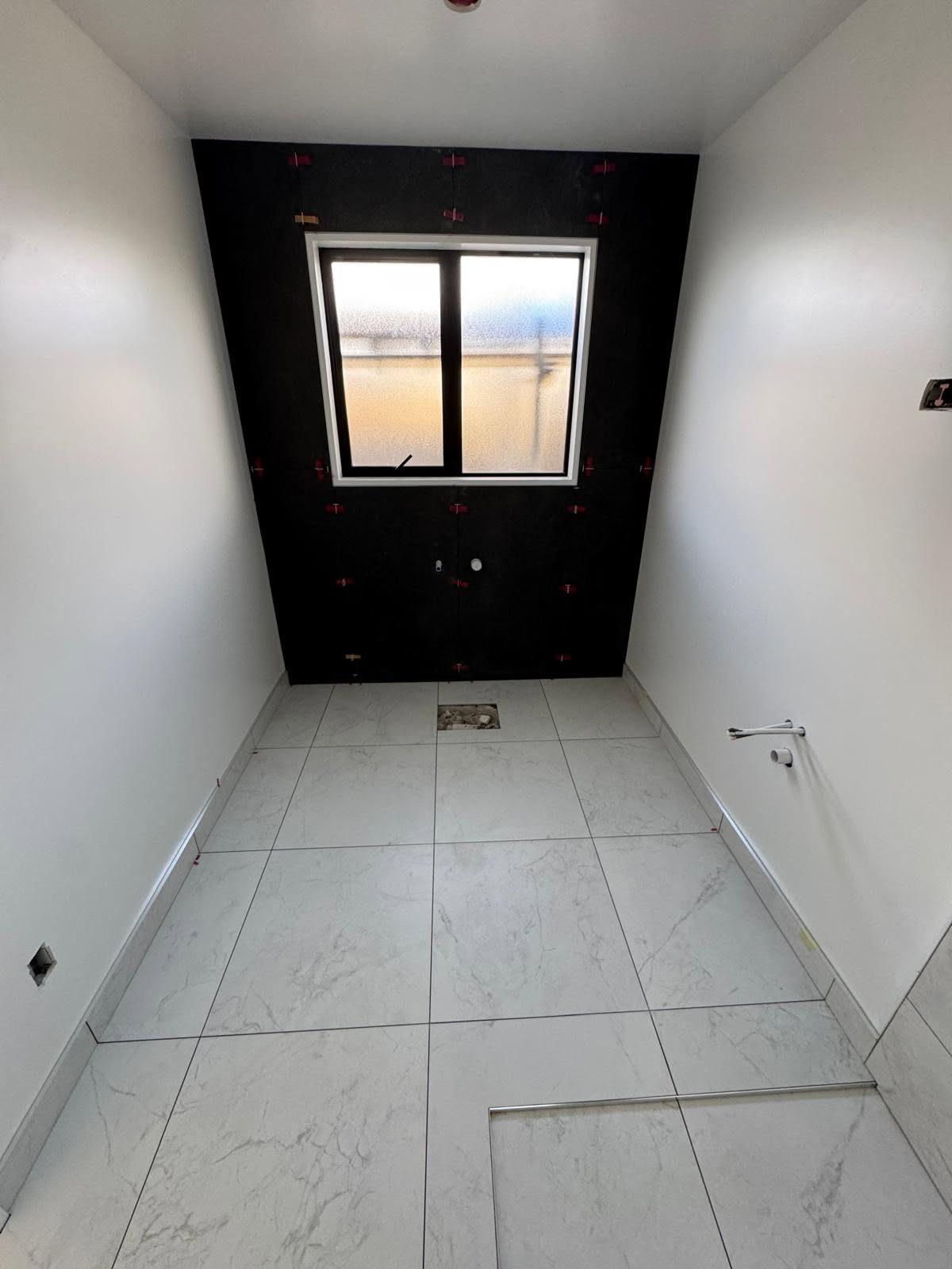 Bathroom floor tiling with a black feature wall