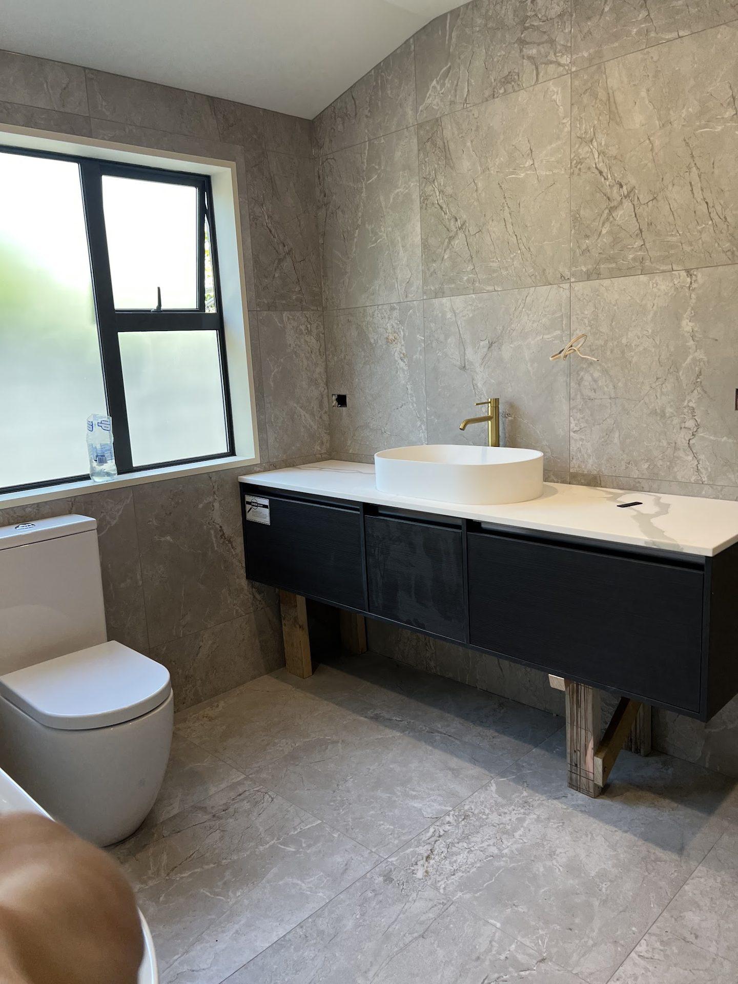 Bathroom with grey stone-look tiles and dark vanity