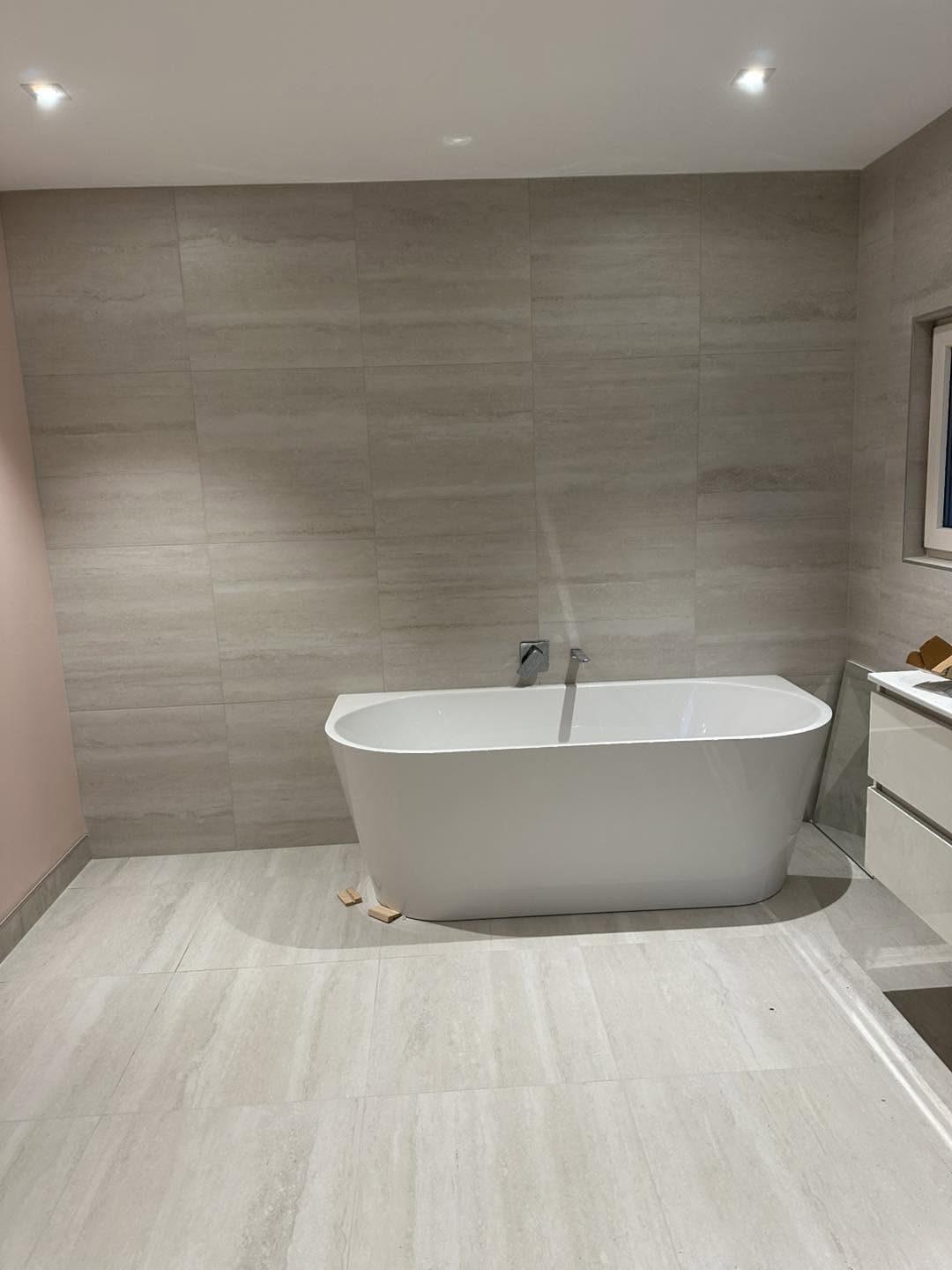 Freestanding bath against floor-to-ceiling tiles