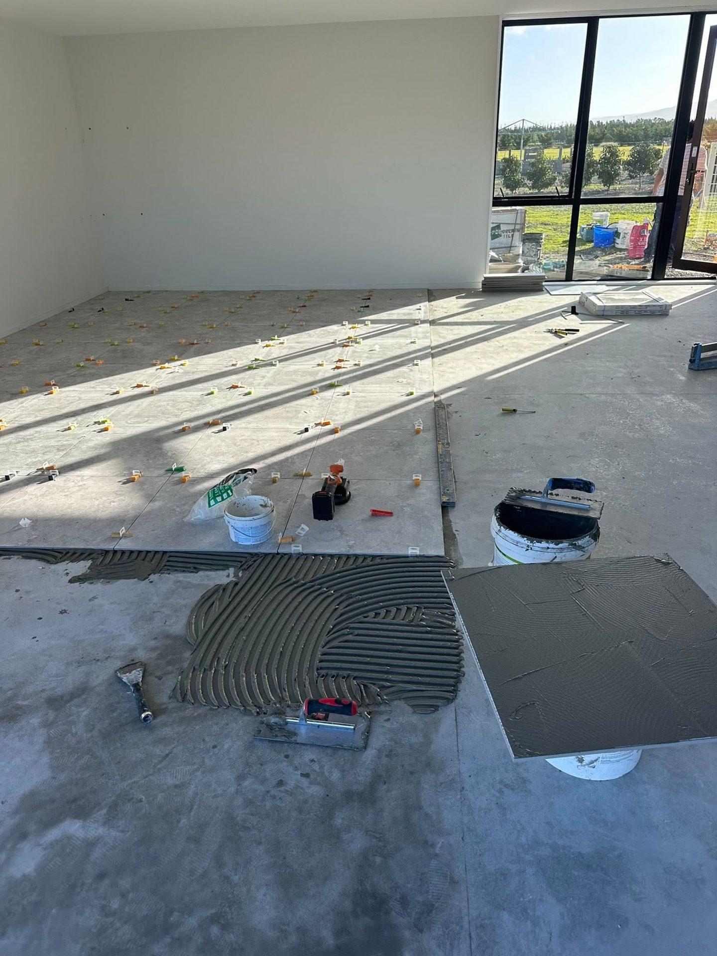 Large-format floor tiles being laid on adhesive in a new build