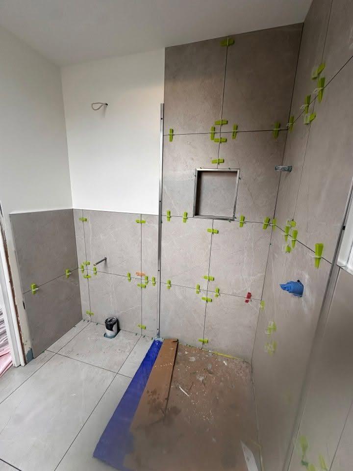 Shower niche being tiled during a bathroom renovation