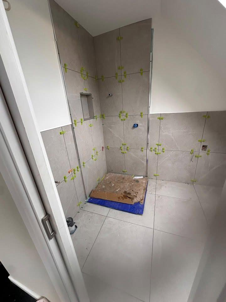 Shower wall tiling in progress using tile levelling clips
