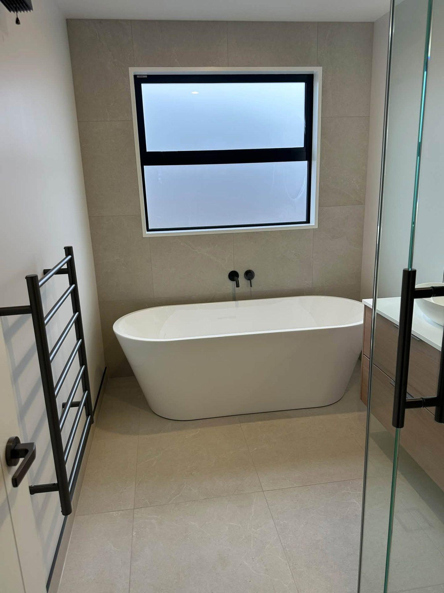 Bathroom with freestanding bath and large-format wall and floor tiles, Christchurch