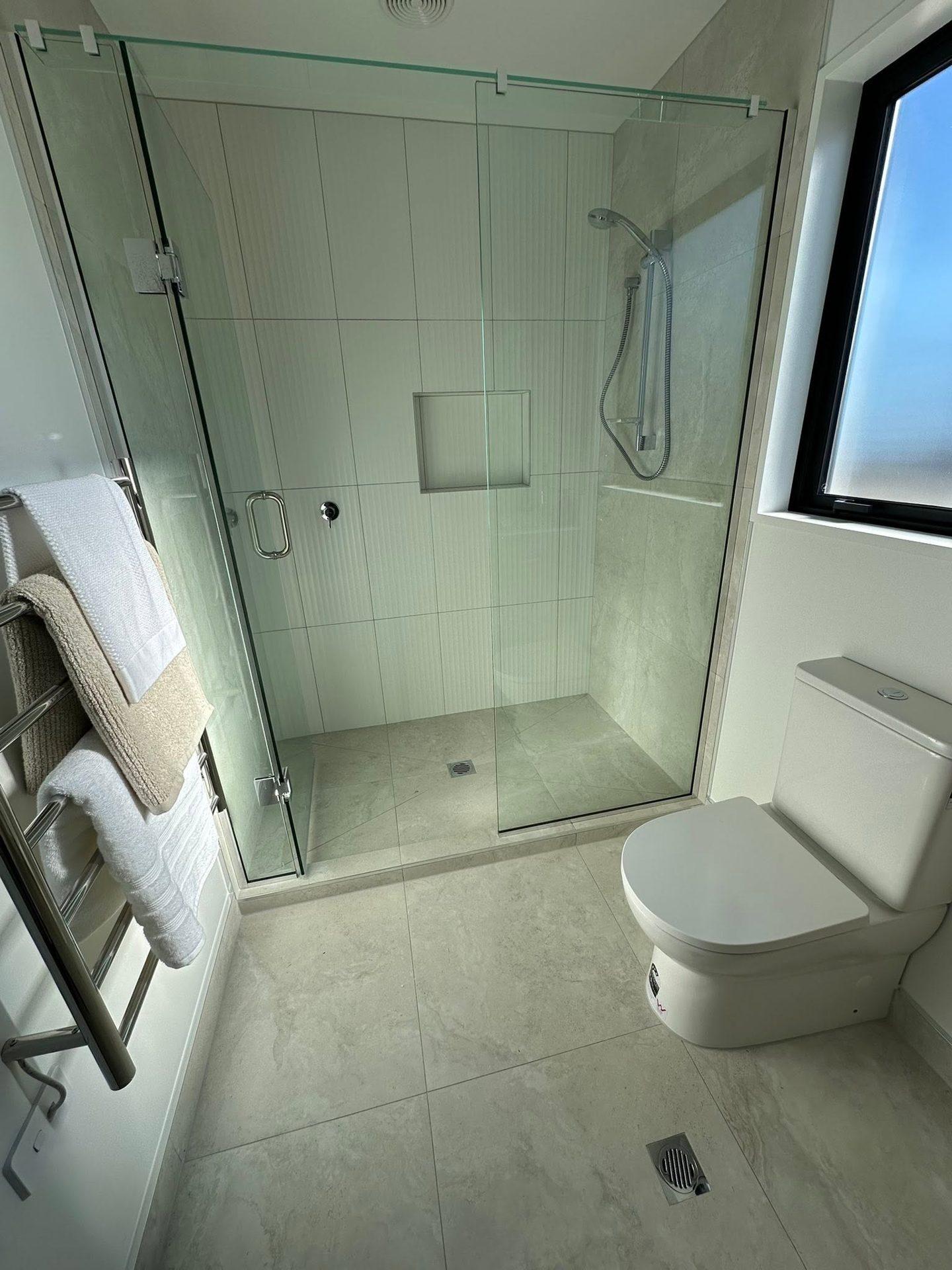 White tiled shower with niche and glass enclosure